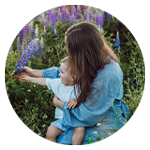 Vuxen och barn plockar blommor i en trädgård.