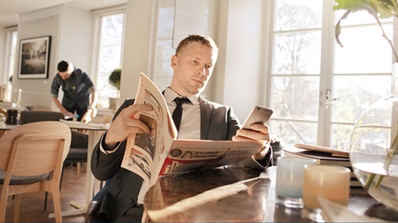 man med tidning och telefon