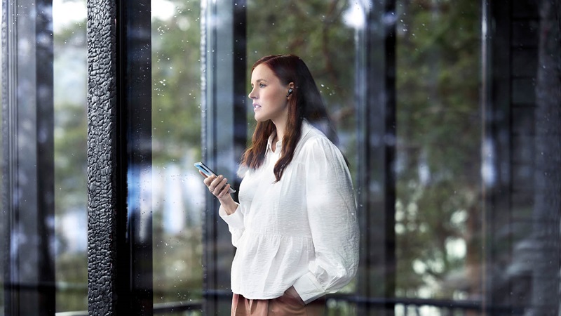 Kvinna står och pratar i mobilen med panoramafönster i bakgrunden.