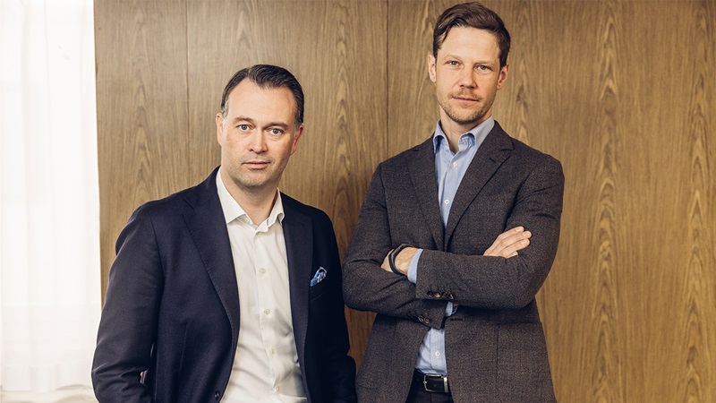 man vid dator tittar på mobil