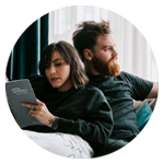 Två personer sitter tillsammans i en soffa, en av dem håller i en bok.